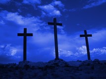 Three crosses of Calvary standing ominously against a dark blue sky 
