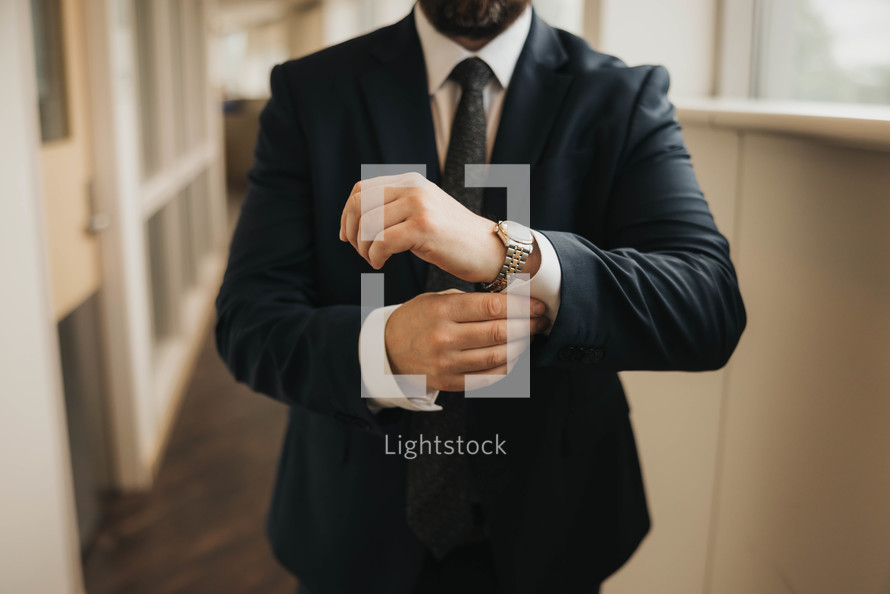 a man in a suit adjusting his watch