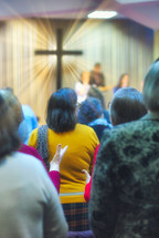 Christian congregation worship God together, with cross with light rays in background