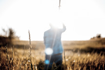 man standing holding a cross in a field 