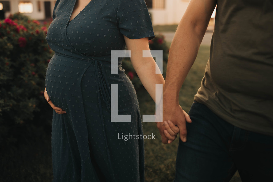 a pregnant woman and her husband hold hands