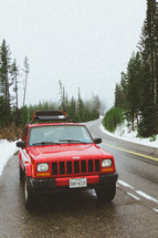 red suv parked on the side of a road and snow
