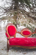 a red couch outdoors in the snow 