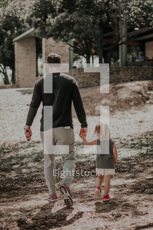 father and daughter walking holding hands outdoors 