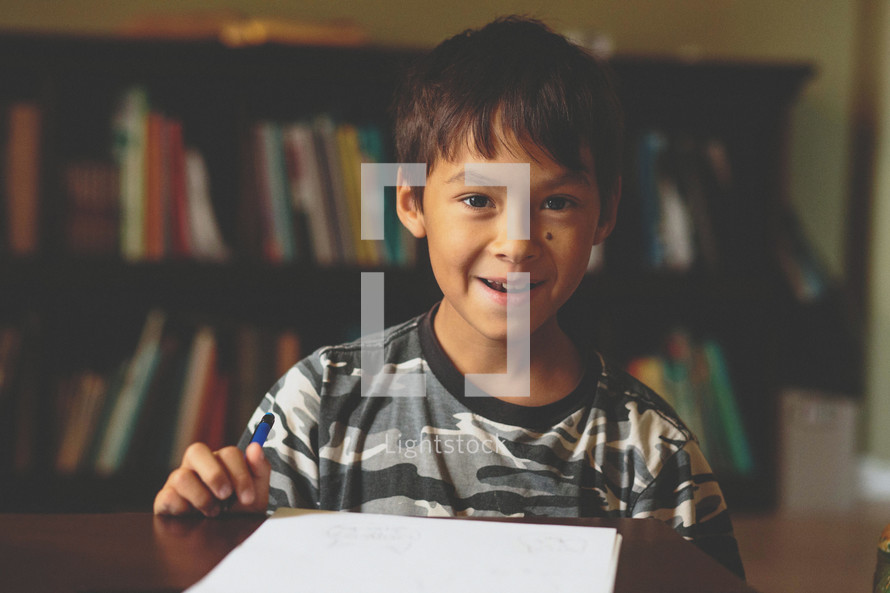A smiling boy doing his homework