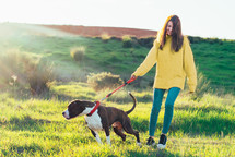 a woman walking her dog in a field 