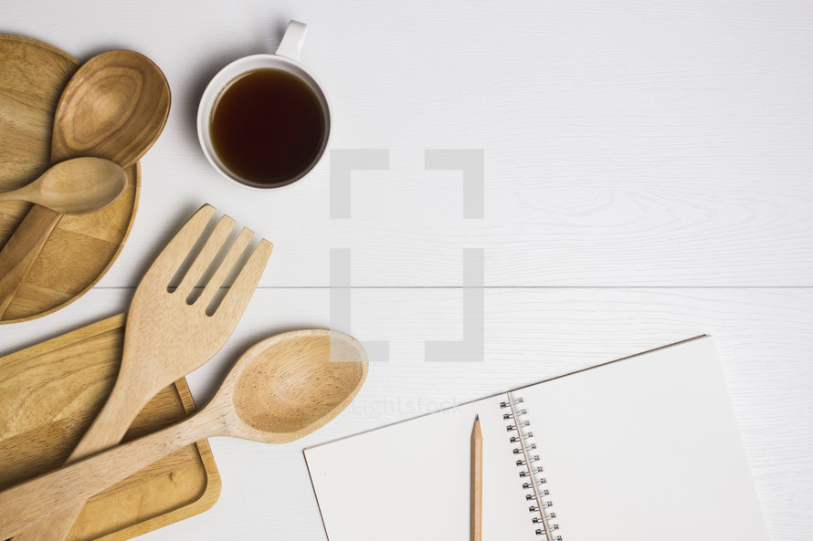wooden spoons, cutting boards, coffee cup, notebook, and pencil 