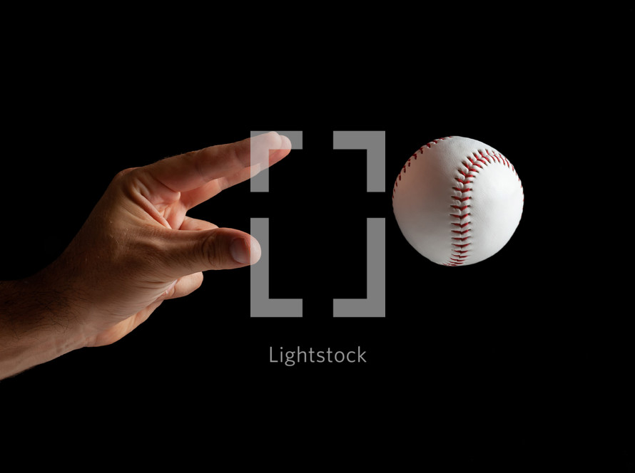 Baseball pitcher, close up of the hand ready to pitch on black background.