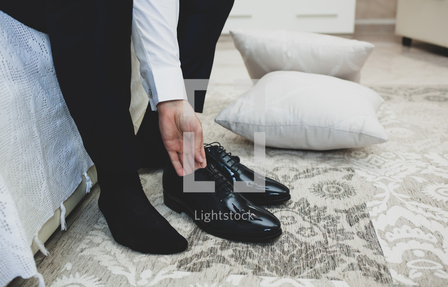 groom putting on shoes getting ready for his wedding 