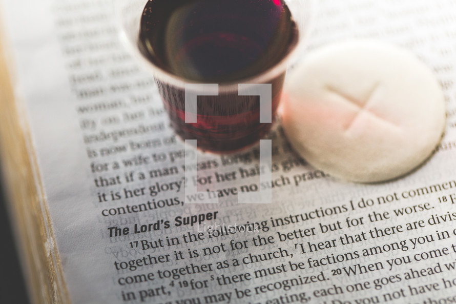 communion wine and bread on the pages of a Bible 