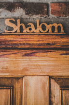 Wooden "shalom" sign over wooden door.
