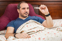 man in the bed with thermometer