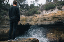 a man standing near a waterfall in New Zealand 