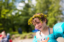 a child in a floatie playing at a lake with a crown of leaves in his hair 