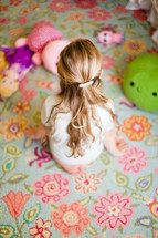child sitting on a rug with toys 