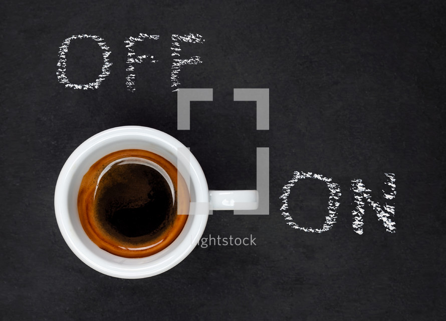 Top view of a Espresso Coffee in small white cup with a lettering ON and OFF on black slate background