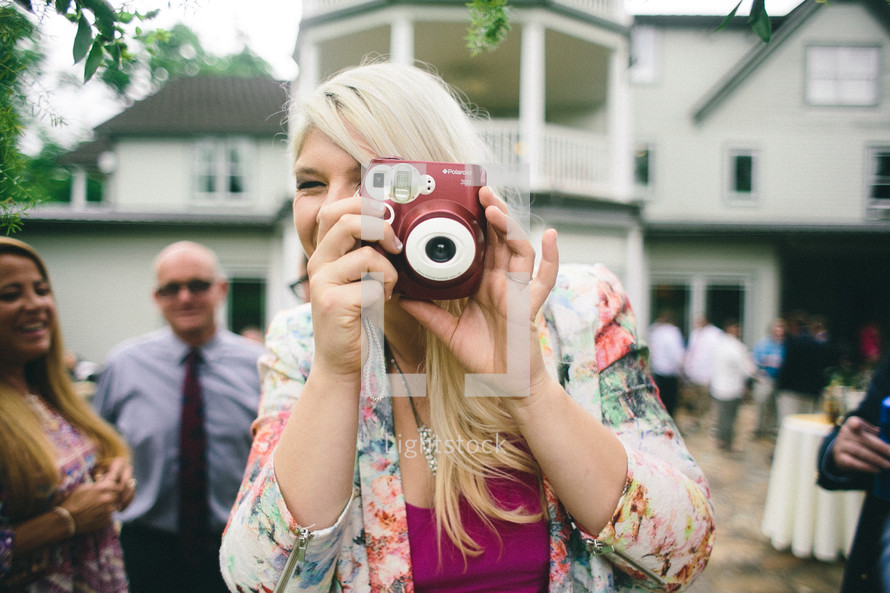 A woman taking a picture with a camera at a wedding reception.