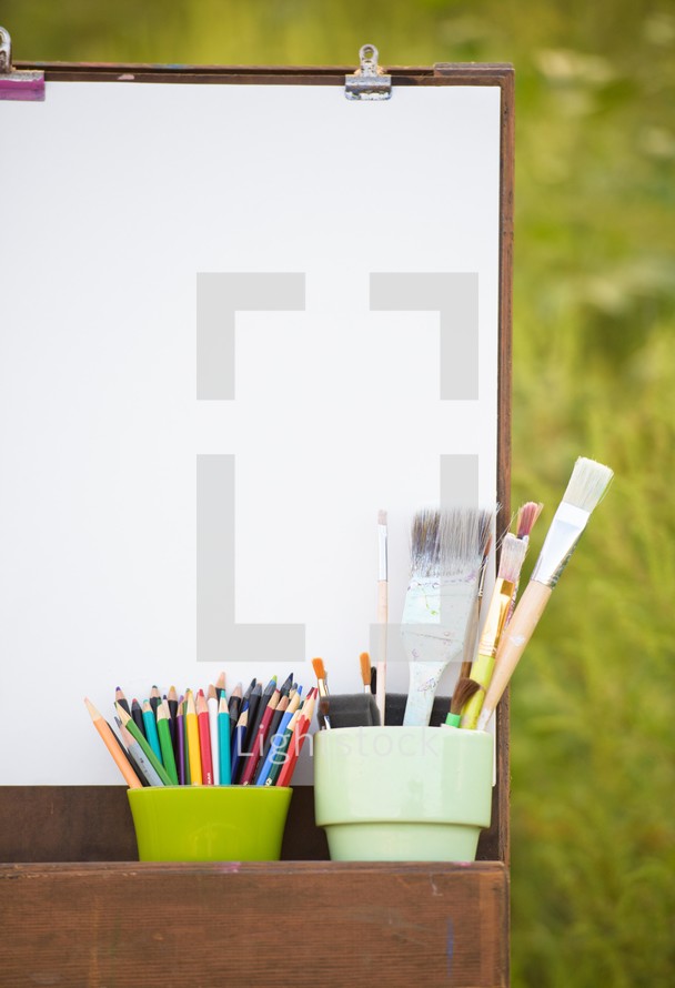 easel, art supplies, and blank canvas outdoors 