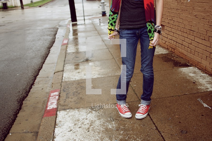 A teenager standing on a sidewalk