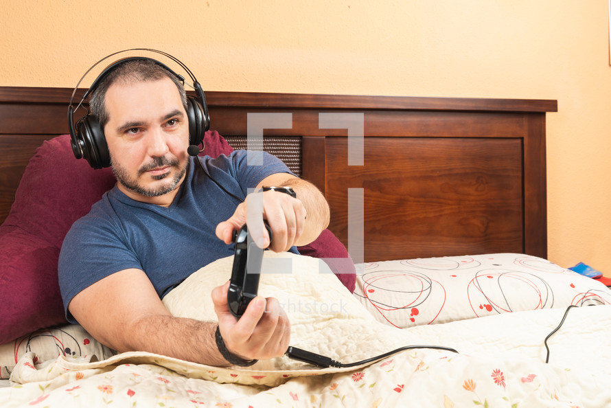 sick man with headphone playing videogames in the bed
