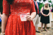 A woman in a red dress holding a drink.