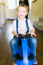 a little boy riding a plasma car in a hallway 