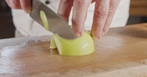 Close up of a chef knife slicing a green apple