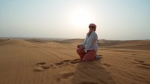 Woman playing with the sand In The Hard Sun Of Arabian Desert