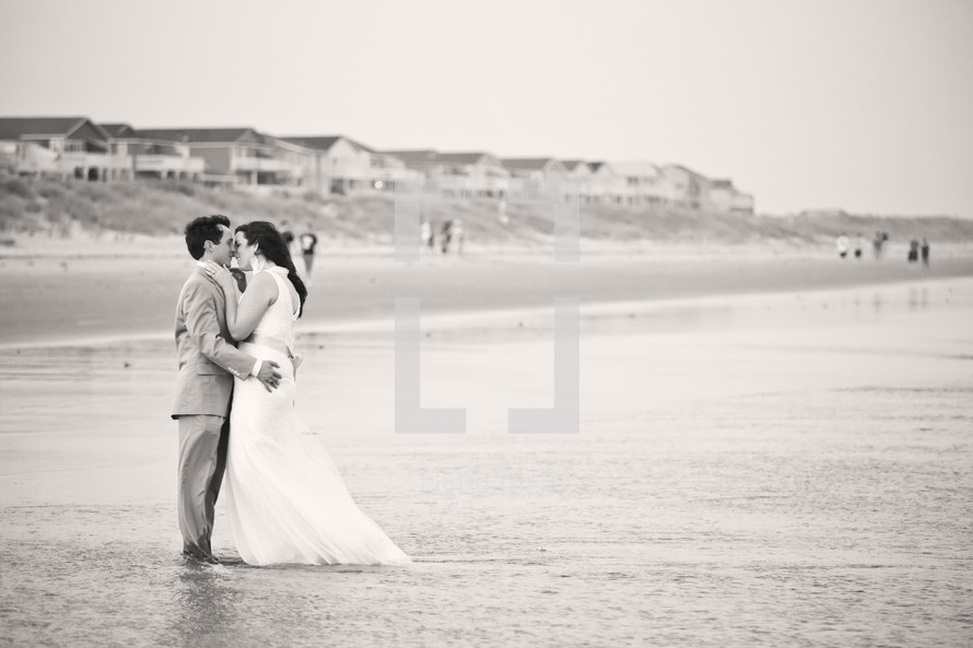 bride and groom kissing on a beach in the water
