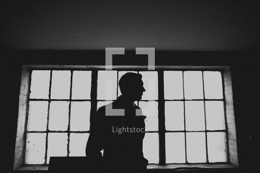 The profile of a groom in front of windows in a warehouse