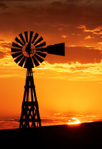 silhouette of a windmill against a golden sunset