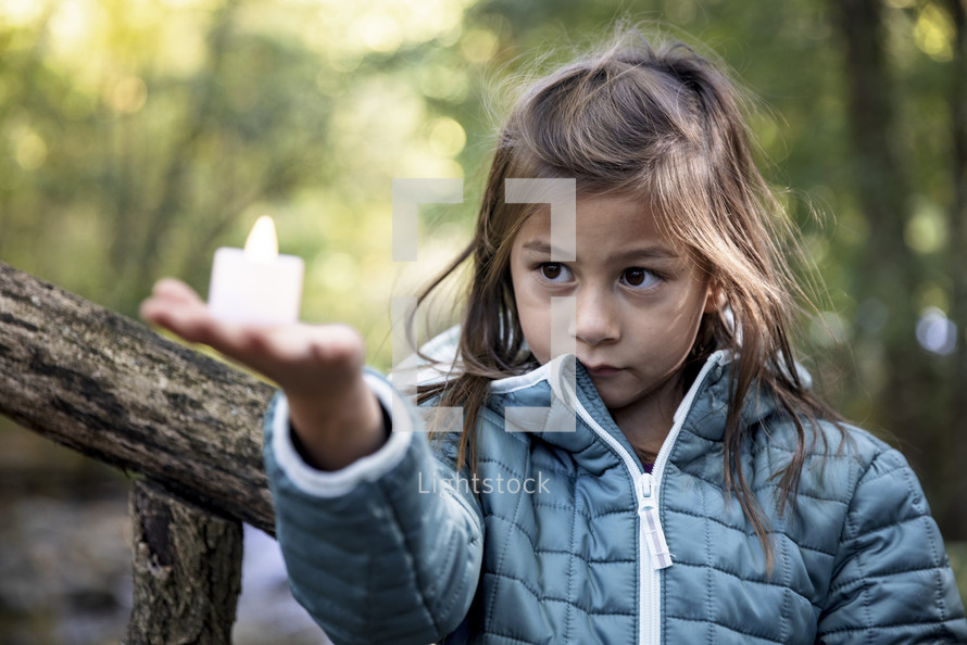 Little girl in a jacket holding a tealight candle