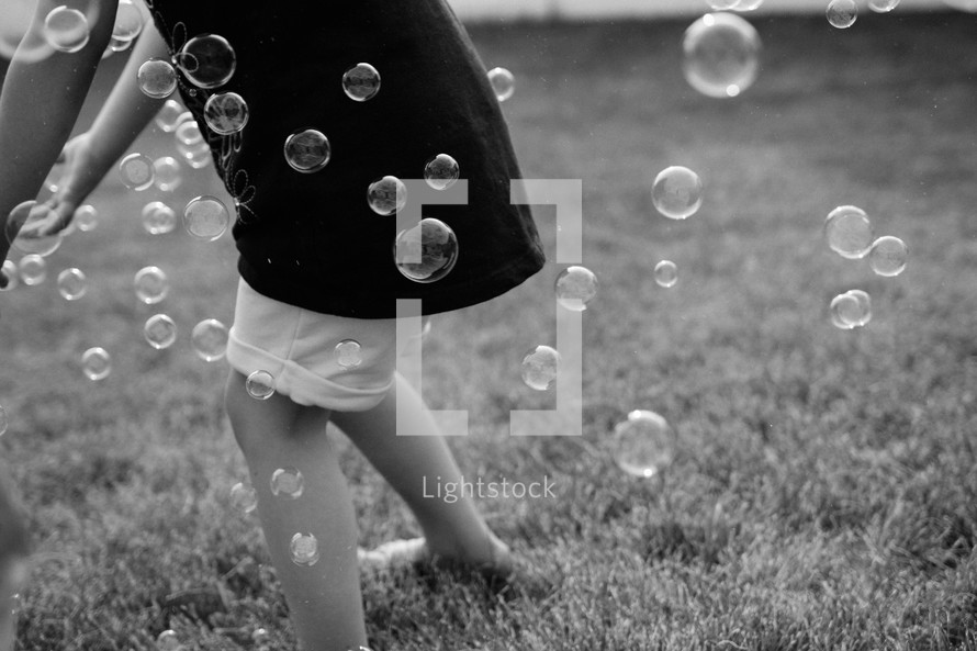 child playing with bubbles in grass 