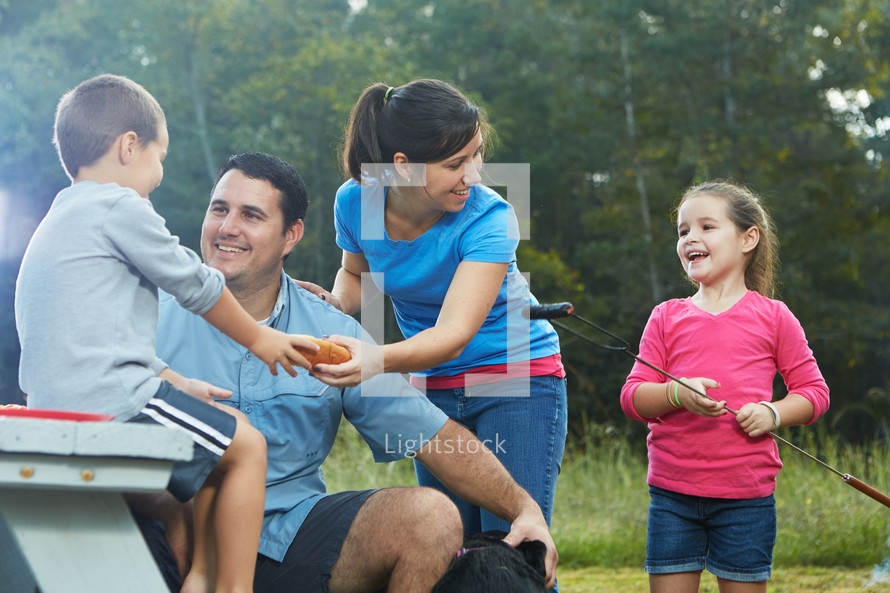 family eating hotdogs at a picnic table 