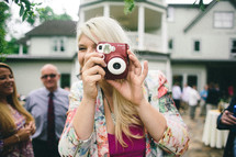A woman taking a picture with a camera at a wedding reception.
