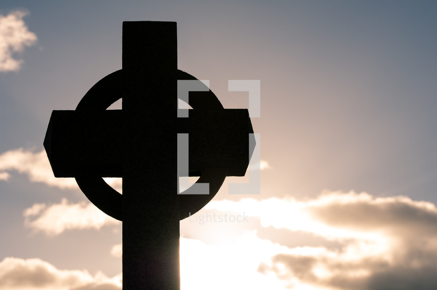 Cross statue with sun and clouds 