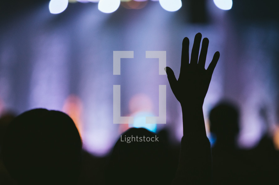 silhouette of a raised hand at a concert