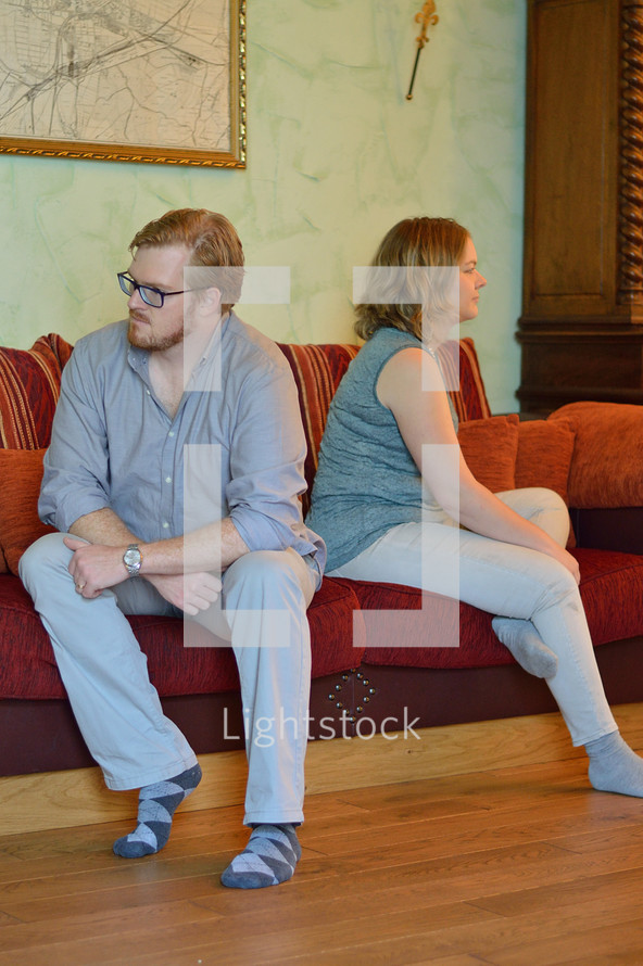 a couple sitting on a couch not speaking to each other 