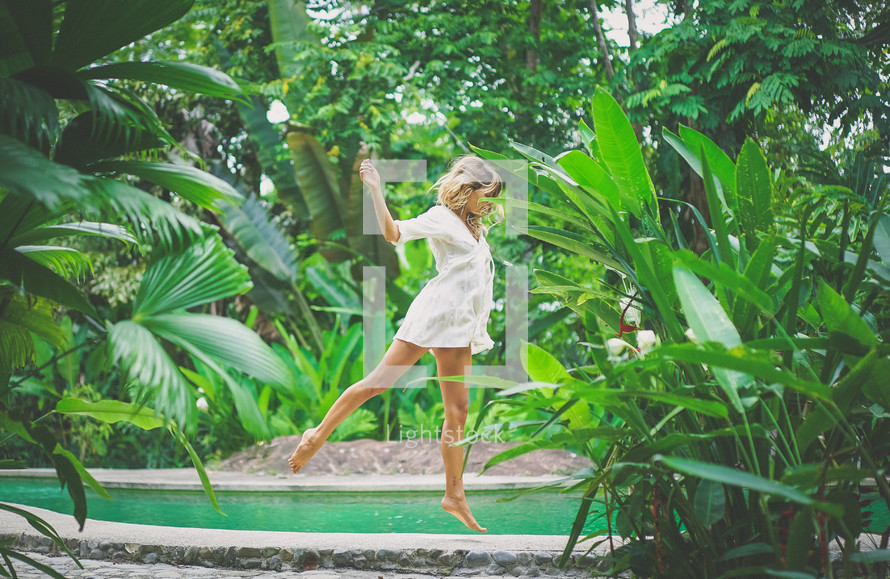 a woman jumping amongst tropical plants 