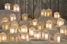 Advent calendar out of 24 self made small white round paper houses illuminated from the inside on white satin for Advent