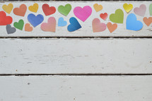 colorful paper hearts on a white wood background 
