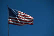 American flag on a pole blowing in the wind.