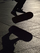 skater jumping on his skateboard with his shadow in evening backlight.