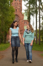 two woman talking walking in front of a church 
