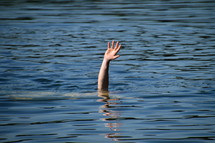a hand raised out of the water for help