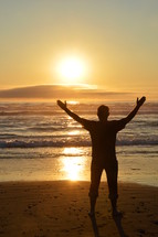 man with raised arms in adoration at the beach. 