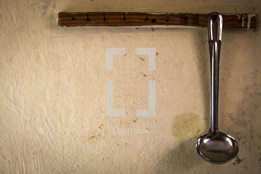 A silver ladle hanging on a wall