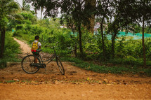 Boy and a bike on a dirt road in Cambodia