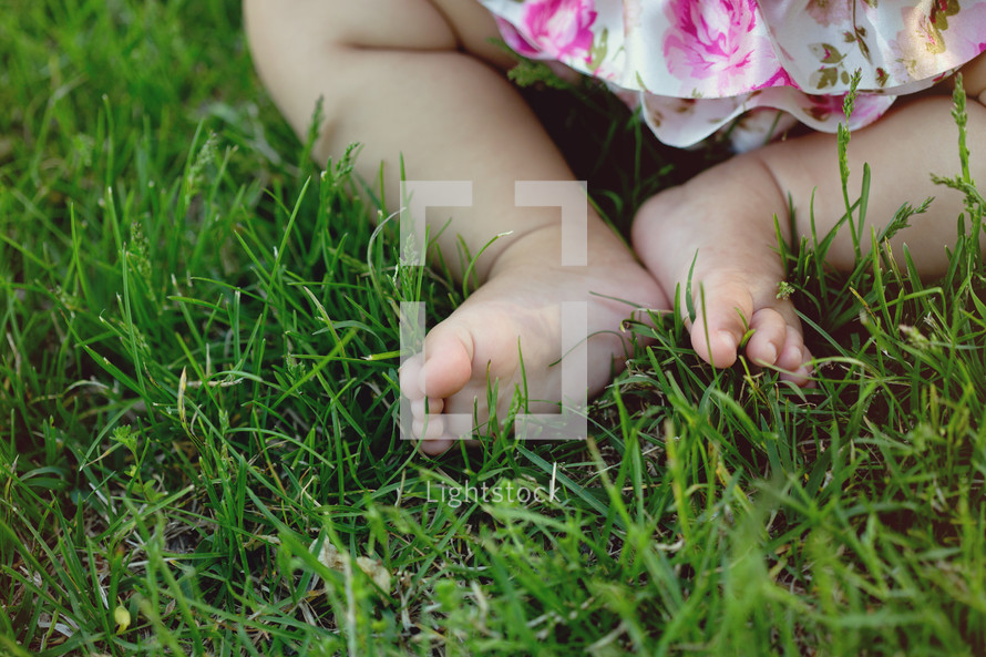 A baby's feet in green grass.