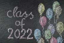 chalk on slate with balloons and the words: class of 2022